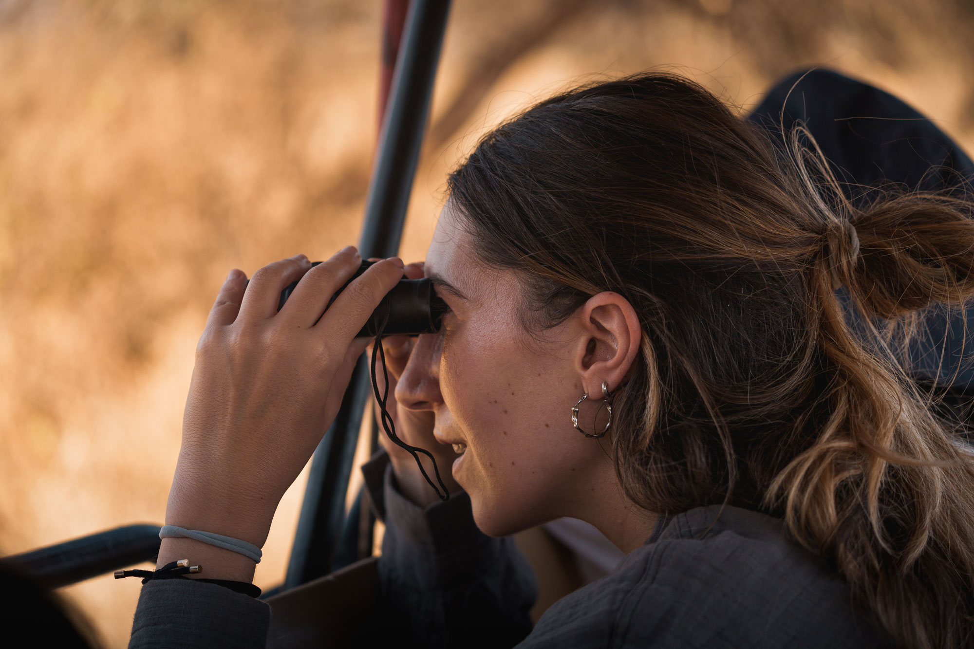 Safari travelers observing wildlife with binoculars during game drive